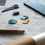 Close-up of a creative workspace featuring schematics, guitar picks, and design tools.