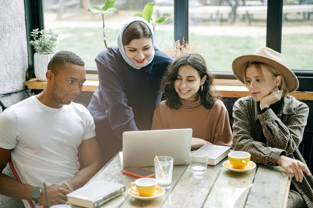 A diverse group of coworkers collaborating on a laptop in a cozy office setting.