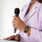 Professional woman confidently speaking at a podium with a microphone.